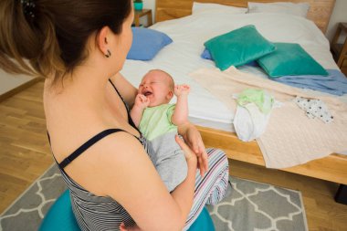 Anne kucağında ve sallanan bebek Fitball 'da oturuyor