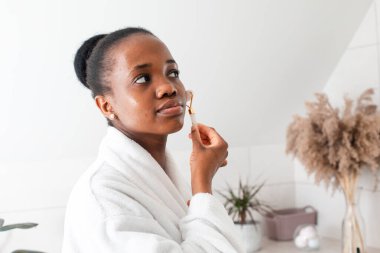 Gülümseyen genç kadın kameraya bakıyor cilt masajı yapıyor.