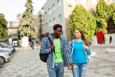 Sırt çantalı iki arkadaş dışarıda konuşuyor.