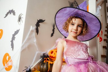 Pembe elbiseli ve cadı şapkalı sevimli kız.