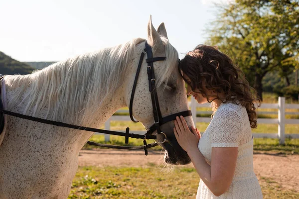 La donna con i capelli ricci si stringe al suo cavallo — Foto Stock