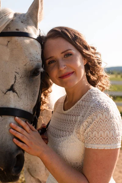 Porträt einer jungen Frau im weißen Kleid, die Pferd umarmt — Stockfoto