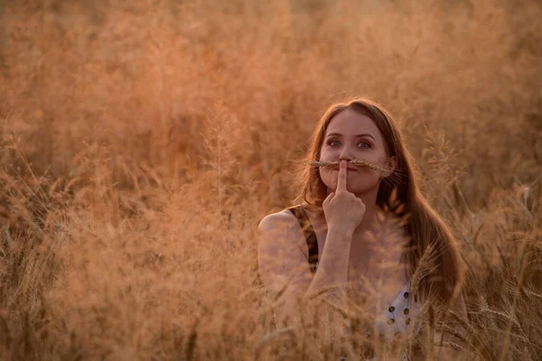 Mujer encantadora posando en el campo jugando con la oreja de centeno — Foto de Stock