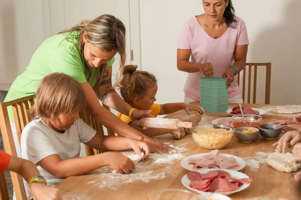 Zwei Frauen mittleren Alters mit kleinen Kindern kochen Pizza — Stockfoto