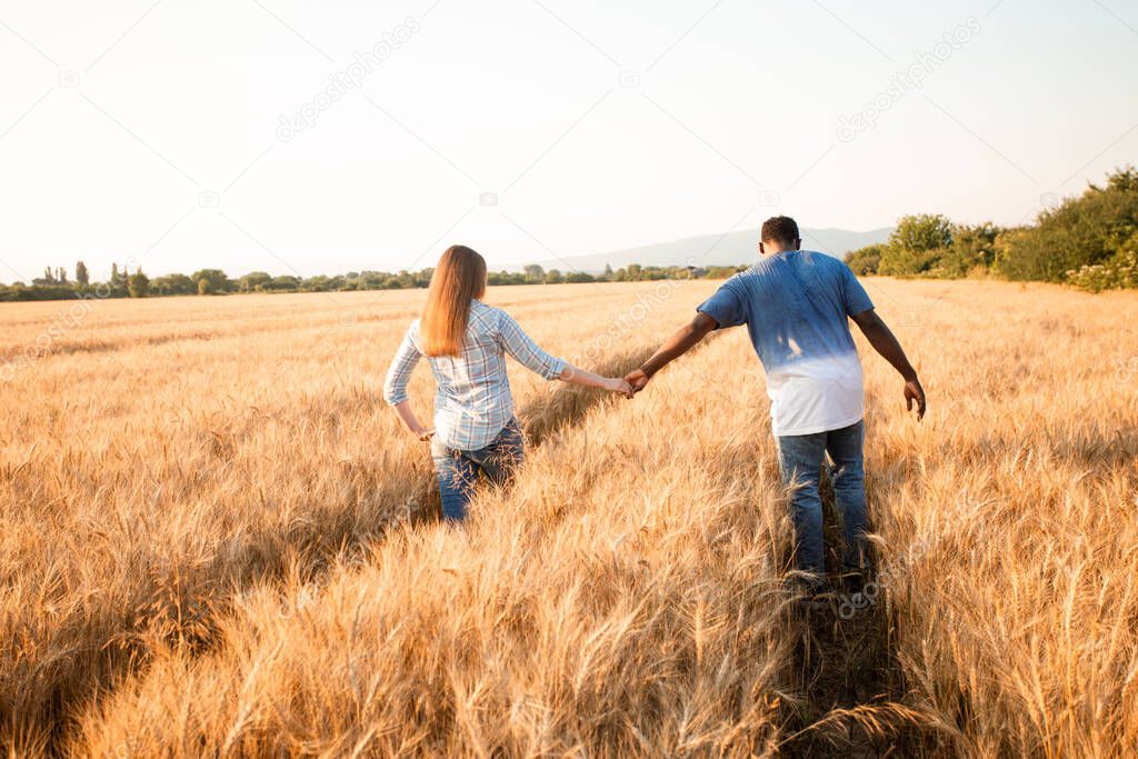 Couple holding hands while walking in field