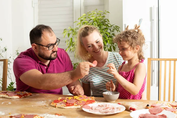 Die glückliche junge Familie kocht hausgemachte Pizza — Stockfoto