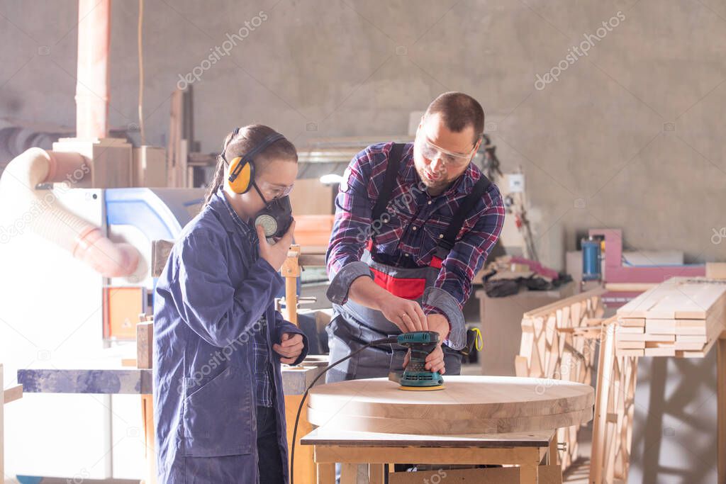 Experienced carpenter teaching young apprentice at workshop