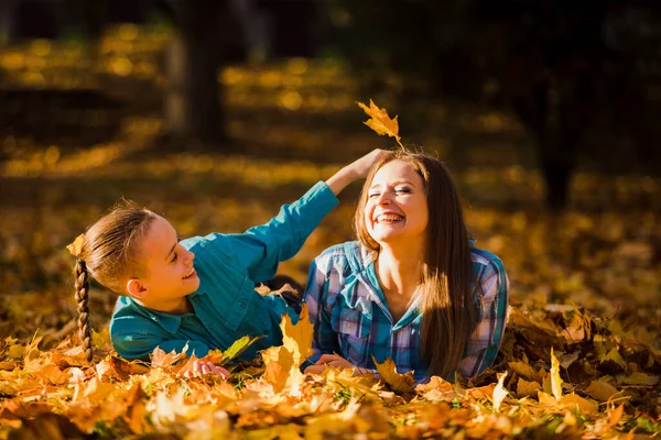 Mutlu anne ve oğul sonbahar akçaağaç yapraklarında saklanarak oynuyorlar. — Stok fotoğraf