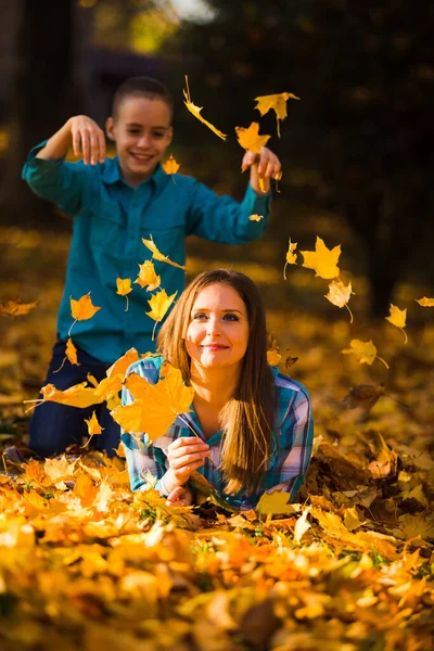 幸せなお母さんと息子は秋のカエデの葉に隠れて遊ぶ — ストック写真