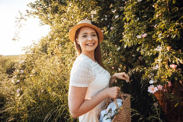Mooie vrouw in hoed houden mand met bloemen — Stockfoto
