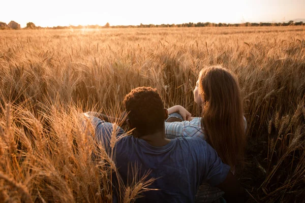 Kucaklaşan çift buğday tarlasında gün batımında buluşuyor. — Stok fotoğraf
