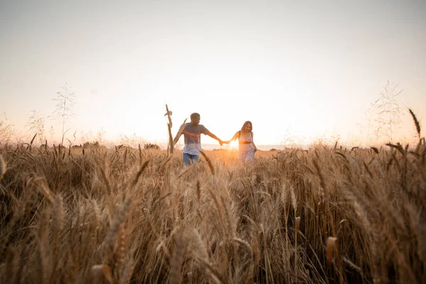 Razza mista giovane coppia adulta che si tiene per mano mentre si cammina nel campo — Foto Stock