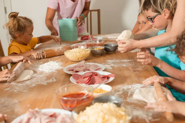 Dos tutoras enseñan a los niños a hacer pizza —  Fotos de Stock