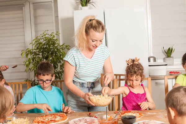 The kids with a teacher are preparing pizza in the kitchen — Stock Photo, Image