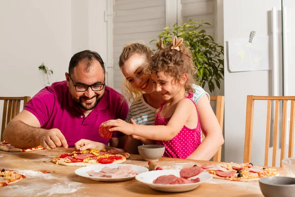 Die glückliche junge Familie kocht hausgemachte Pizza — Stockfoto