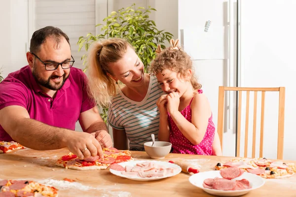 Счастливая молодая семья готовит домашнюю пиццу — стоковое фото