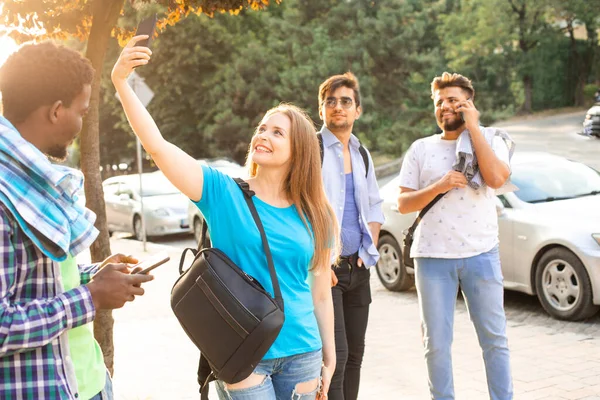 The multi-cultural students with smartphones walk in the city — Stock Photo, Image