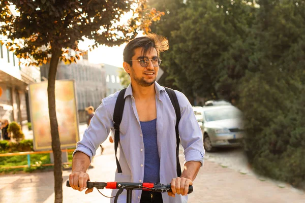 Szczęśliwy student jeździ skuterem elektrycznym w mieście — Zdjęcie stockowe