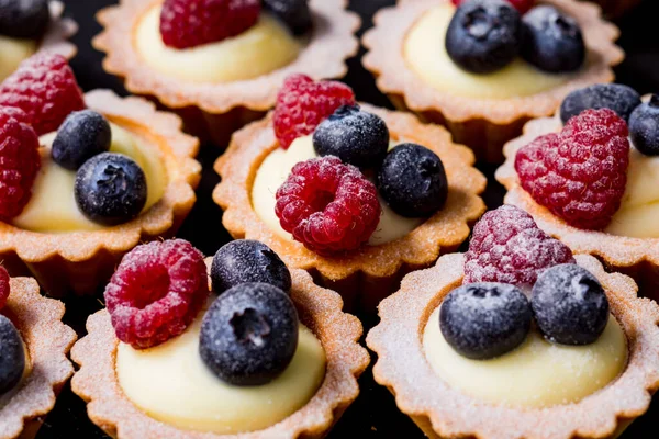 Zavřít tartalety s vanilkovou smetanou a čerstvými malinami a borůvkami — Stock fotografie