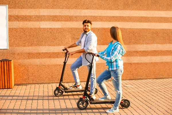 Młoda para spędza razem czas jeżdżąc na skuterze elektrycznym w mieście. — Zdjęcie stockowe
