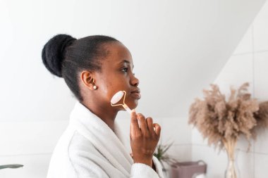 Gülümseyen genç kadın kameraya bakıyor cilt masajı yapıyor.