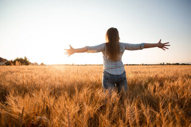 Barışçıl kadın doğan güneşi tarlada karşılıyor.