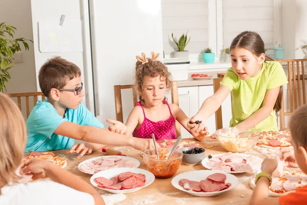 Přátelé spolu sedí u stolu v kuchyni a dělají pizzu — Stock fotografie