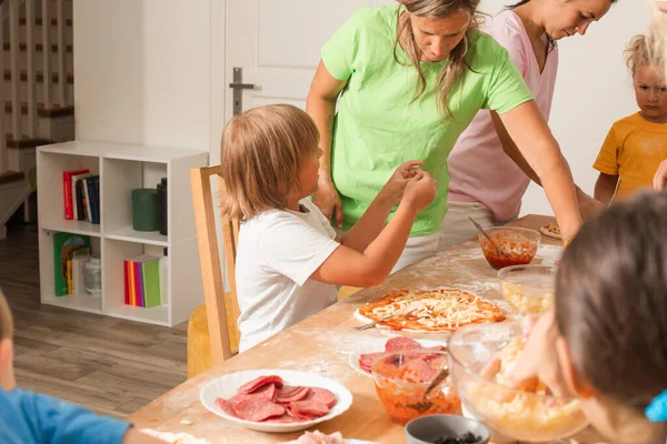 Skupina matek s dětmi dělá pizzu — Stock fotografie
