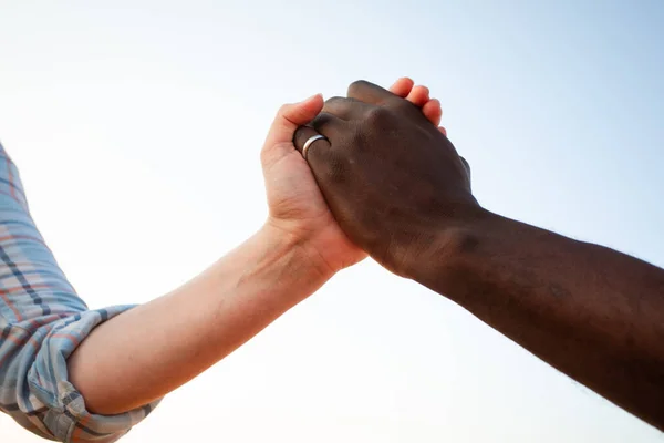 Relazione multirazziale e concetto di amicizia. Due mani che tengono insieme. — Foto Stock