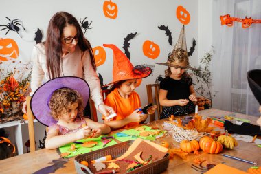 Öğretmen yaratıcı çocuklara kağıt yer imleri yapmaları için yardım ediyor