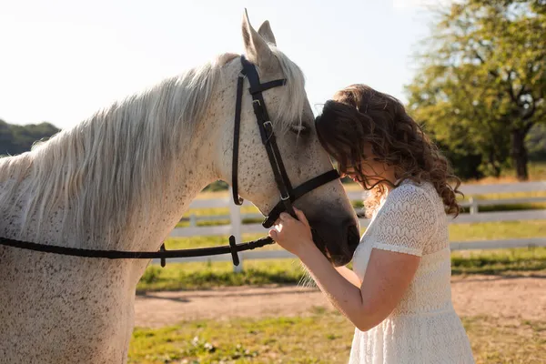 Die Frau mit den lockigen Haaren schmiegt sich an ihr Pferd — Stockfoto