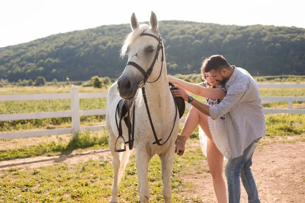 Der junge Mann hilft seiner Frau aufs Pferd — Stockfoto