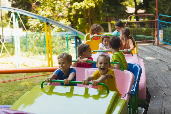 遊園地のジェットコースターの上の幸せな子供たち — ストック写真