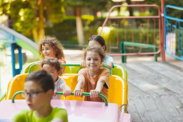 Los niños felices en una montaña rusa en el parque de atracciones — Foto de Stock