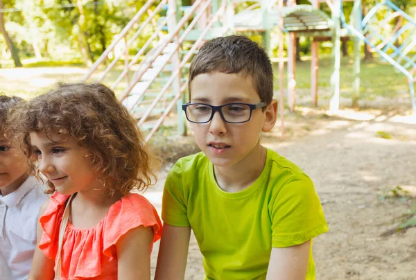 De glada barnen sitter på en bänk i parken. — Stockfoto