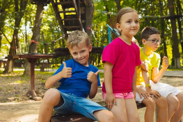 Les enfants heureux sont assis sur un banc dans le parc — Photo