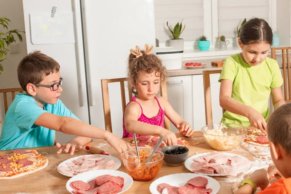 Amigos juntos sentam-se em uma mesa na cozinha e fazem pizza — Fotografia de Stock