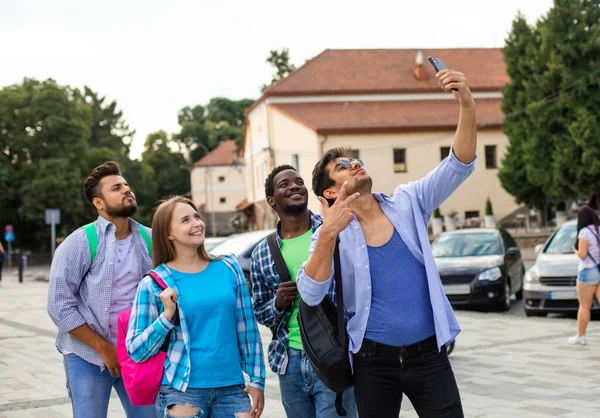 O grupo alegre de estudantes multiétnicos que tomam uma selfie ao ar livre — Fotografia de Stock