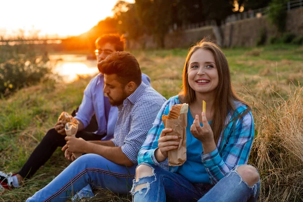 De unga multietniska studenterna äter snabbmat på campus — Stockfoto