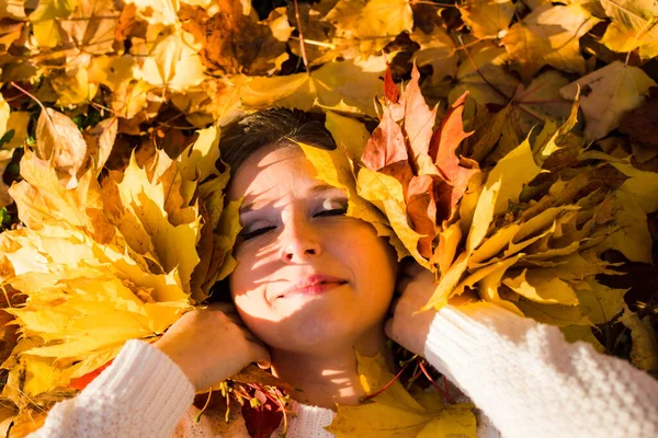 Woman laying in maple leaves in the park. — Stock Photo, Image