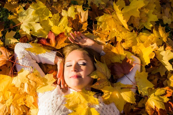 Donna sdraiata in foglie d'acero nel parco. — Foto Stock