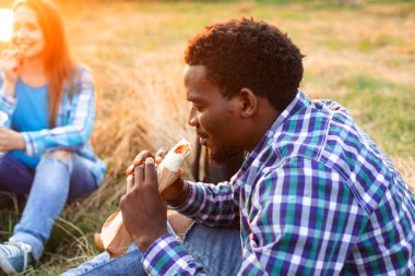 Mutlu lise öğrencisi dışarıda oturmuş kebap yiyor.