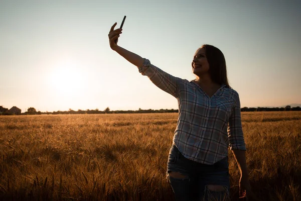 Mladá dívka se selfie v létě pšenice pole — Stock fotografie