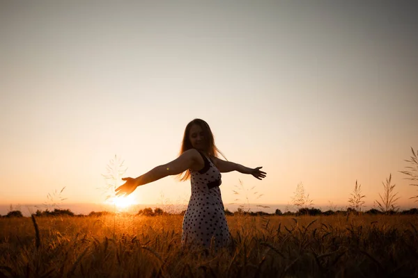 Friedliche Frau begrüßt die aufgehende Sonne auf dem Feld — Stockfoto