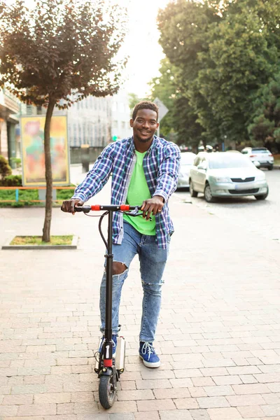 Młody człowiek ze skuterem pozuje w mieście. — Zdjęcie stockowe