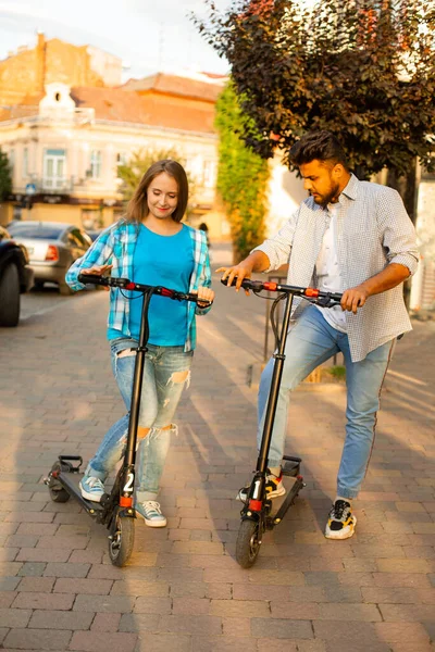 Kochająca się para jeździ na skuterach elektrycznych i patrzą na siebie — Zdjęcie stockowe