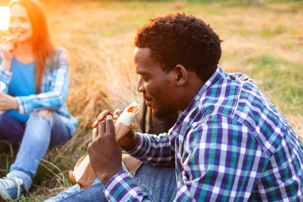 Den glada gymnasieeleven sitter utomhus och äter kebab — Stockfoto