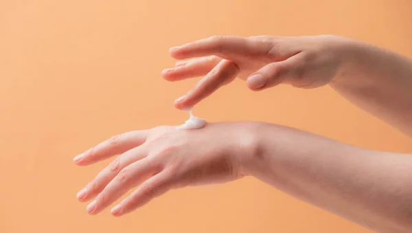 Manos femeninas jóvenes aplicando crema o loción — Foto de Stock