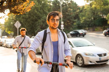Mutlu öğrenci şehirde elektrikli scooter kullanıyor.