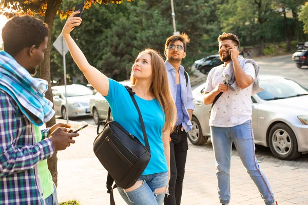 Multikulturní studenti s chytrými telefony chodí po městě — Stock fotografie